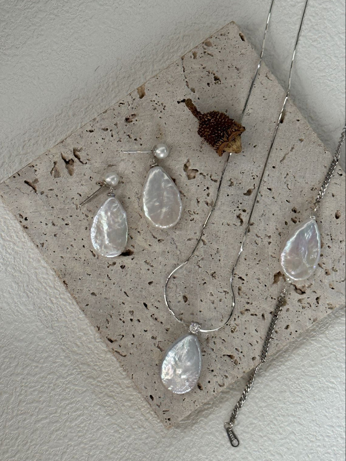 Teardrop-shaped earrings on a concrete surface