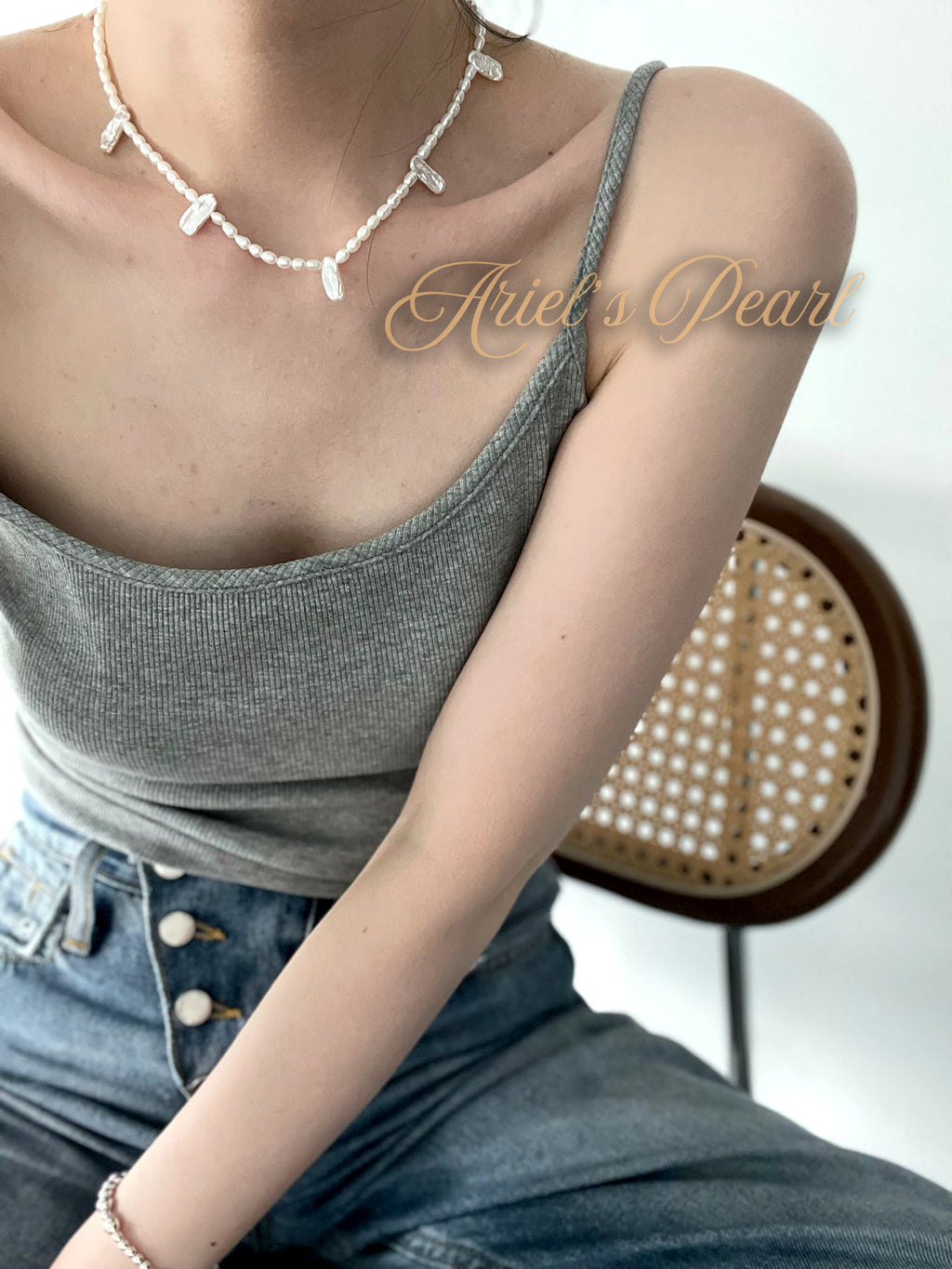 Person wearing a pearl necklace with a blurred background