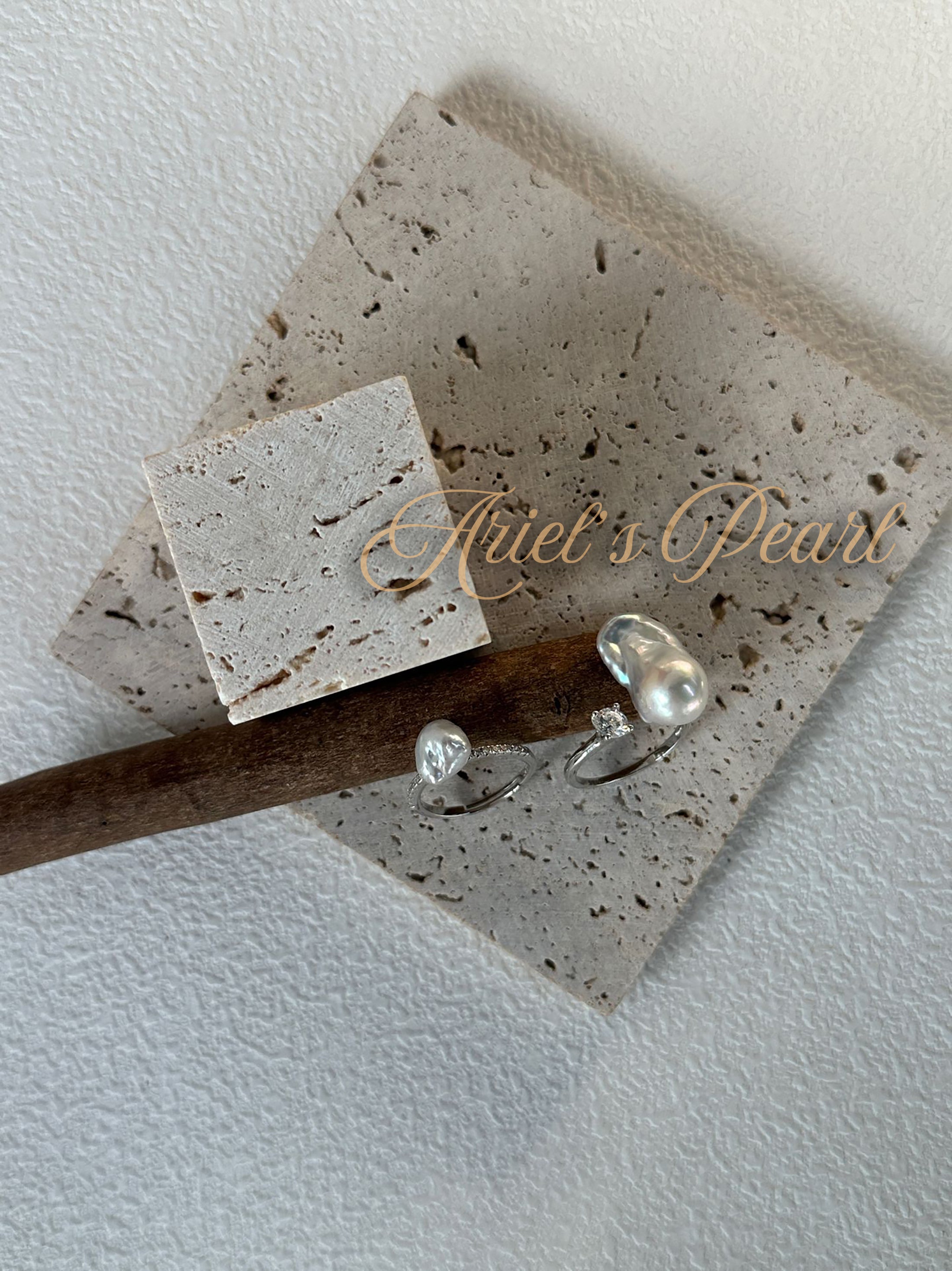 Silver Pearl rings on a stone surface with 'Ariel's Pearl' branding.