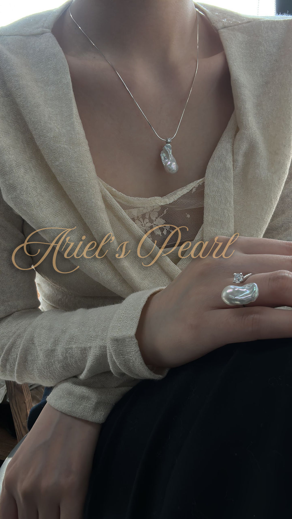 Person wearing a pearl necklace and ring with 'Ariel's Pearl' branding.