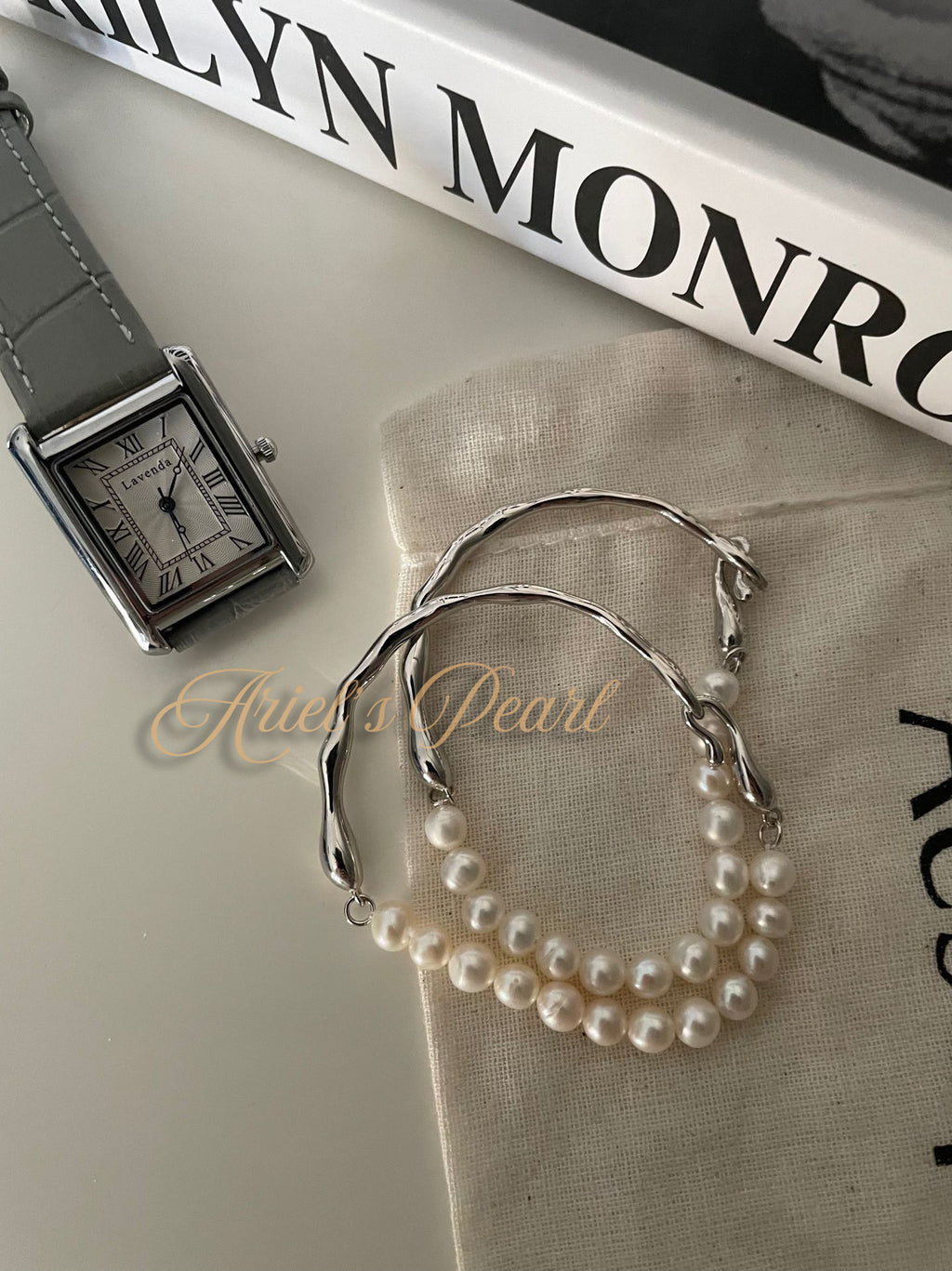 2 Pearl bracelets and a watch on a surface