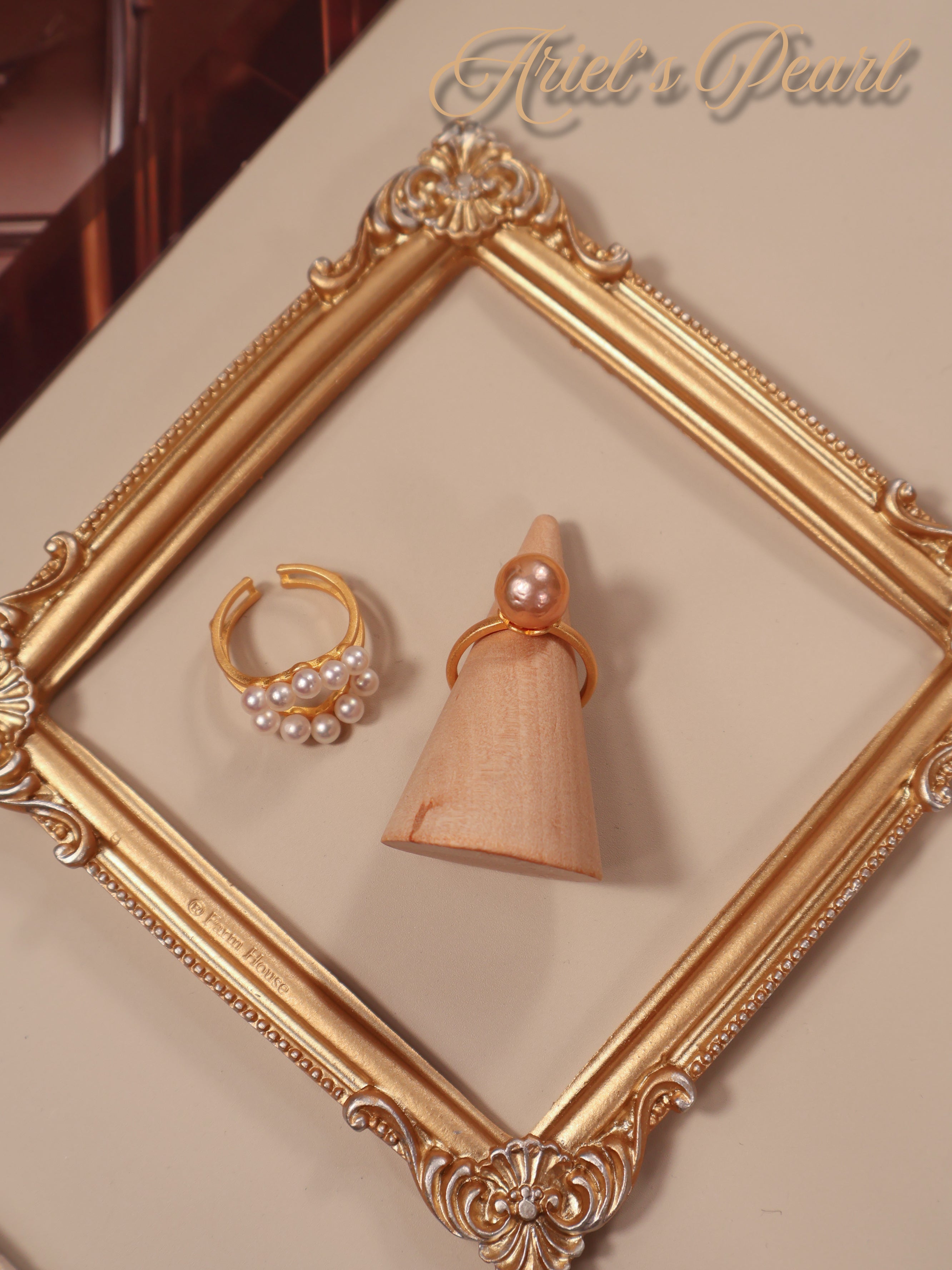 Gold Ring set in a decorative gold frame, featuring 'Ariel's Pearl' branding.